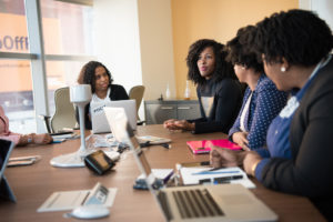 Women of color working around a conference table.