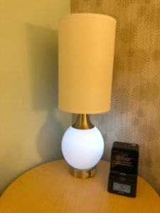 A table lamp. It has a tall cylindrical shade which covers a standard light bulb, and a large round base that glows like the moon.